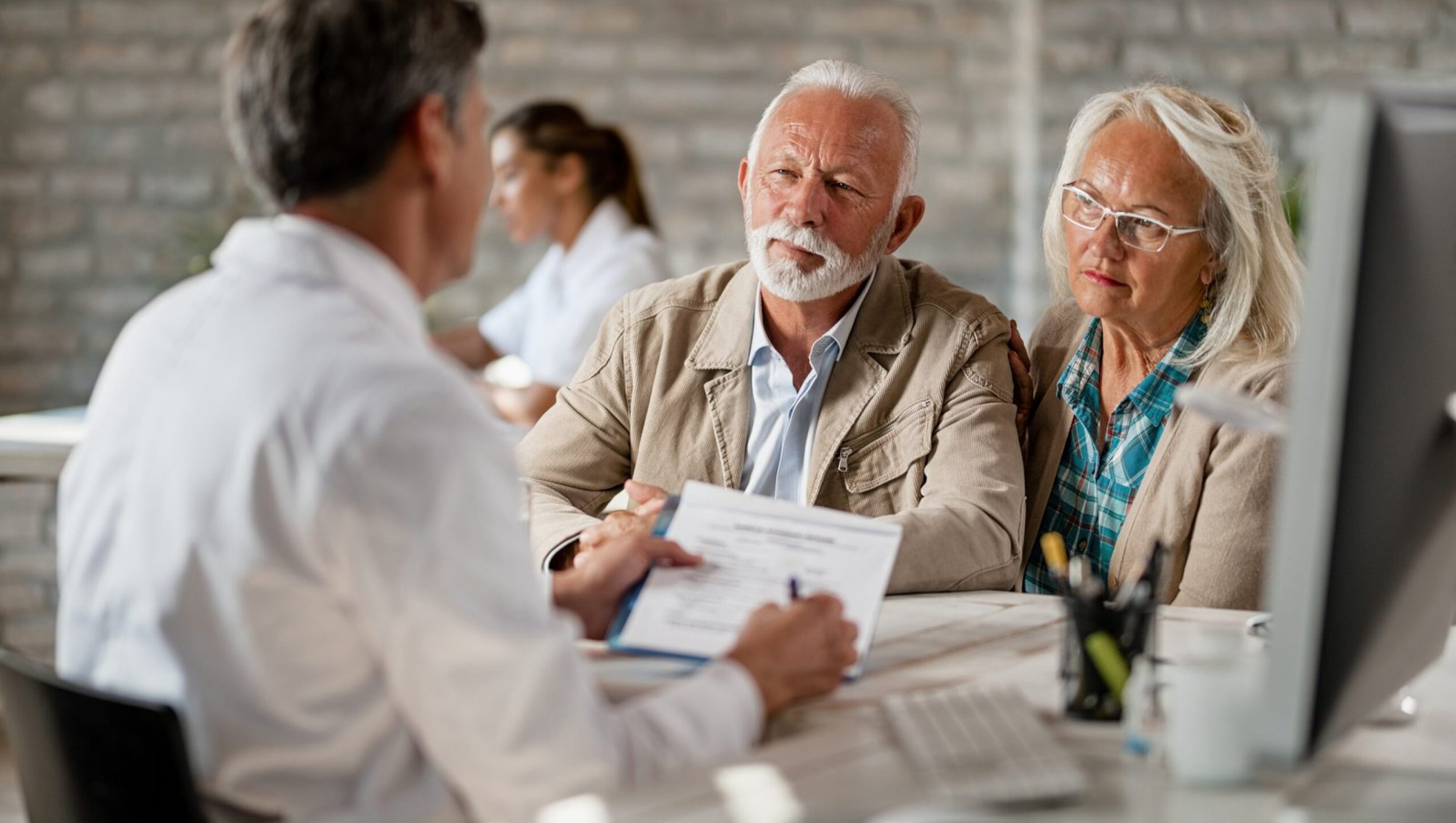 senior-couple-consulting-with-healthcare-worker-about-their-insurance-policy-while-having-meeting-clinic-scaled.jpg